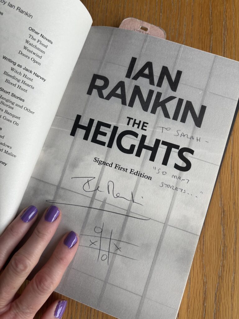 The Heights by Ian Rankin, Signed copy of The Heights by Ian Rankin, Book review, A book called The Heights by Ian Rankin is held open on the title page by a hand with purple nails and it is signed To Sarah with a noughts and crosses sketch