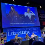 Suede at Cheltenham Literature Festival, Silent Sunday, My Sunday Photo, Four middle aged men sit in front of a blue background which says Cheltenham Literature Festival and two of them are visible on a large screen above their heads
