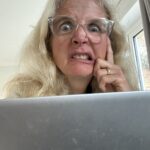 Thoughts from my head, Blogging, Blogger, A middle aged woman with long blonde hair and glasses sits behind a silver laptop and pulls a funny face